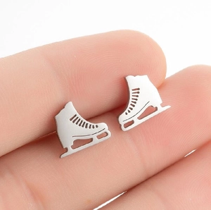 Boucles d'oreilles patins à glace en acier inoxydable présentées sur le doigt
