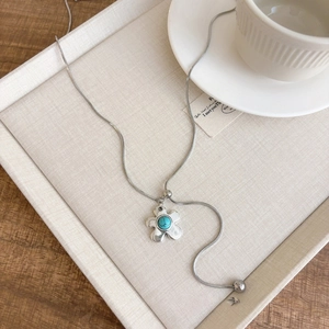 Macro shot of silver flower pendant necklace with turquoise stone and snake chain detail