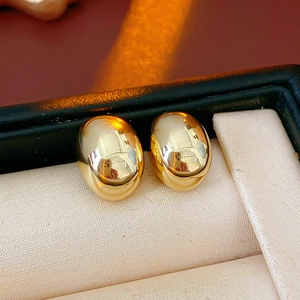 Macro view of gold plated mirror finish stud earrings resting in a luxury jewelry box