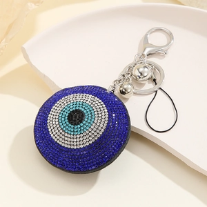 Turkish Evil Eye keychain with blue rhinestones and tassels on a beige paper background