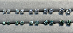 Detailed comparison of various sizes and colors of moissanite stud earrings on a tray