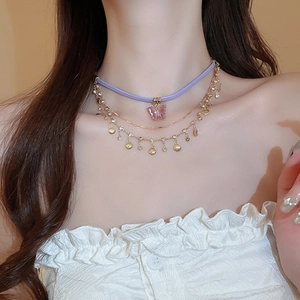 Detail view of multi-layer necklace with purple butterfly and gold shell pendants
