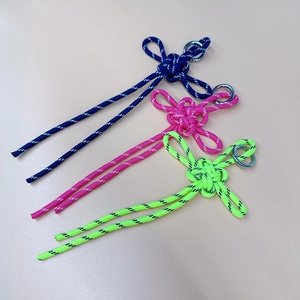 Three handmade colorful braided knot keychains with silver metal rings on beige background
