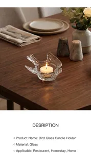 Detail of bird-shaped glass candle holder with tealight candle on a wooden table