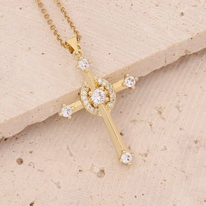 Macro shot of gold cross pendant with micro-pave zircons on a beige stone background