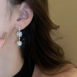 Detail of silver drop earrings with star pattern and sparkling round zircon stone