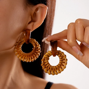 Detail of round woven rattan earrings with amber resin links on a model's ear