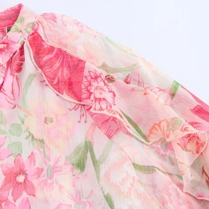 Detail of floral chiffon fabric with ruffles and vertical texture on a pink blouse