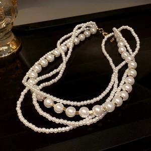Macro shot of multi-layer white pearls and gold metal spacers on a glossy black surface