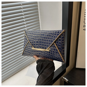 Close-up of deep blue crocodile textured envelope clutch with gold metal V-trim details