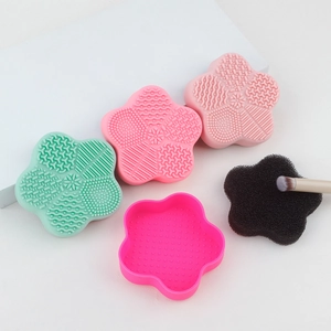 Macro shot of petal-shaped silicone makeup brush cleaning mats and sponge in pink and green