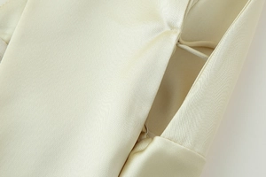 Macro view of champagne satin dress showing fine stitching and invisible metal fasteners