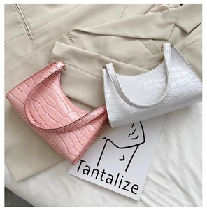 Detail of pink and white faux leather underarm bags with glossy crocodile pattern texture