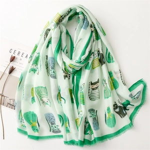 Mint green scarf with cute cartoon cat prints and frayed edges on a white background