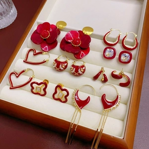 Détails de boucles d'oreilles en émail rouge et or dans un coffret en bois
