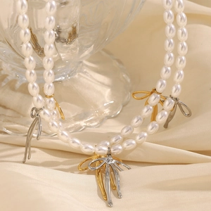 Collier de perles à deux rangs avec pendentifs nœuds dorés et argentés sur soie