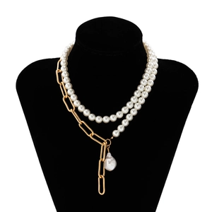 Detail of layered gold chain necklace featuring a white baroque pearl drop on a black bust
