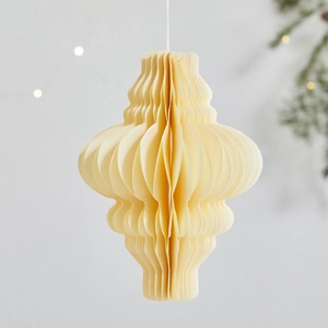 Beige honeycomb paper lantern ornament hanging in a cozy Christmas holiday scene