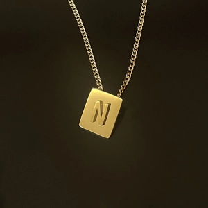 Macro shot of 18K gold plated square pendant with embossed letter N on a fine chain