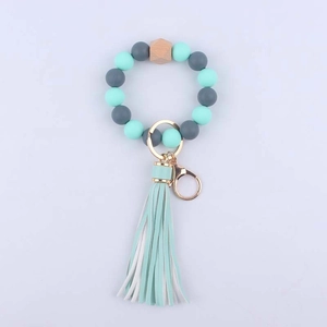 Detailed view of mint green silicone beaded wristlet with beech wood bead and PU tassel