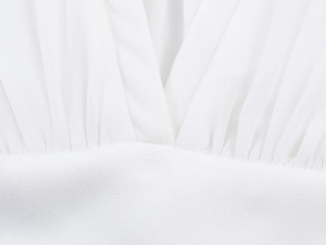 Détail d'un chemisier blanc col en V montrant le tissu plissé et la texture de la taille