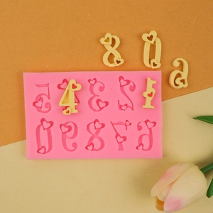 Dettaglio dello stampo in silicone rosa con numeri 0-9 a cuore e decorazioni pronte