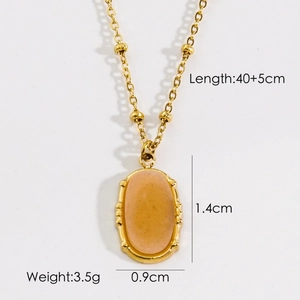 Detail view of a gold beaded chain necklace with an oval orange-pink gemstone pendant