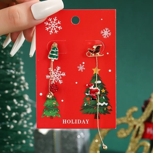 Detail of asymmetric Christmas earrings with Santa on a sled and festive bells