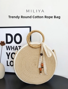 Detail of round cotton rope woven handbag with lace bow and wooden beads on black surface