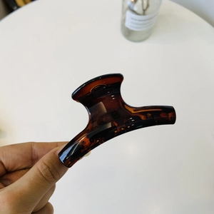 Macro detail of tortoiseshell hair claw clip in dark brown amber resin with spring mechanism