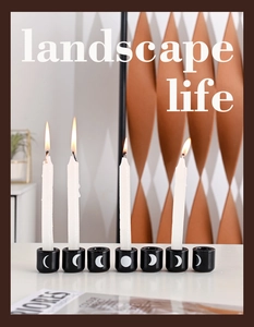 Close-up of black ceramic candle holders with moon phase patterns and white candles