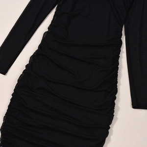 Détail de la robe en maille noire avec fronces latérales et texture transparente sur beige