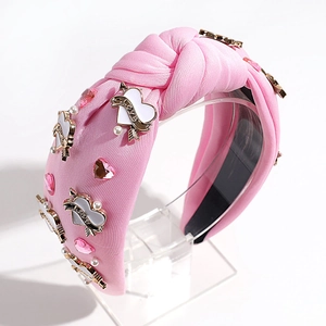 Detail of pink knotted headband with heart charms, pearls and pink rhinestones on a stand