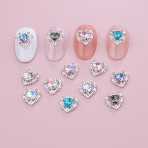 Macro view of multi-color heart-shaped nail charms with rhinestones on pink background