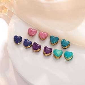 Luxurious stainless steel heart earrings in five glitter colors on a silk background