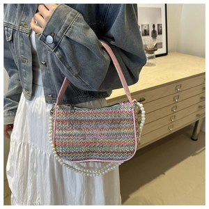 Detail of colorful woven straw bag with pink butterfly embroidery and large pearl chain