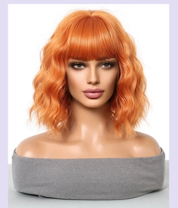 Detailed view of short orange wavy bob wig with bangs on a mannequin head
