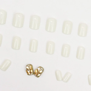Faux ongles blanc laiteux avec paillettes champagne et strass ambrés pour manucure