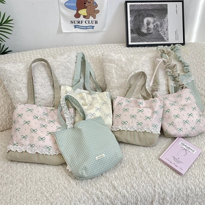Detailed display of several lace canvas handbags on a plush white sofa setting