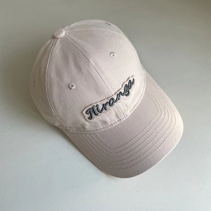 Detailed view of apricot cotton baseball cap featuring dark Hiranga embroidery and curved brim