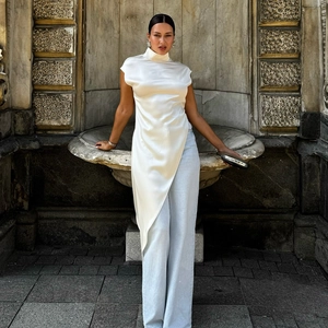 Detail of elegant white satin sleeveless mock neck top with a stylish draped asymmetric hem