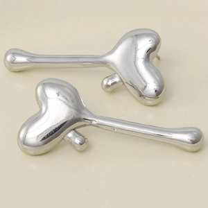 Macro shot of liquid metal heart drop earrings in polished silver finish on beige base