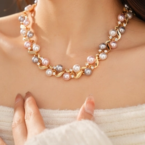 Détail d'un collier vintage avec perles roses et grises et feuilles d'or strassées