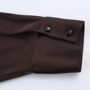 Close-up of elegant satin shirt cuff featuring two dark buttons with metallic shine finish