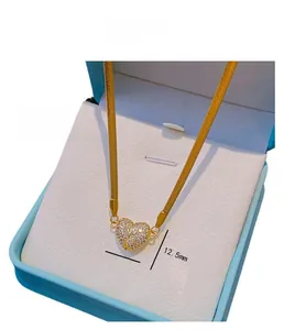Macro shot of gold-plated heart pendant with full crystals and flat snake chain detail