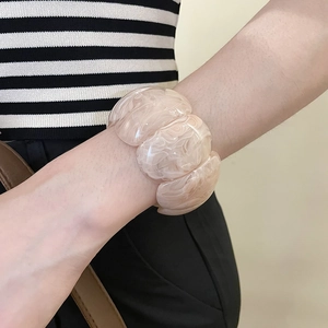 Close-up of a wide acrylic resin bracelet with pink marble pattern on a wrist