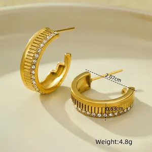 Macro detail of 18K gold geometric earrings with striped texture and cubic zirconia inlay