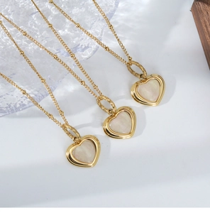 Detail of elegant gold heart pendant necklaces with luminous white mother of pearl inlay