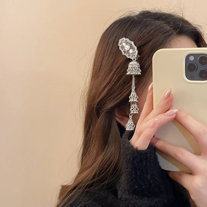 Ethnic silver tassel hair clip with bells shown being worn on long dark hair side view