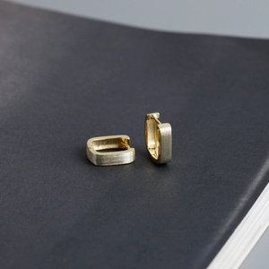 Macro detail of 18K gold plated rectangular earrings with textured brushed metal finish